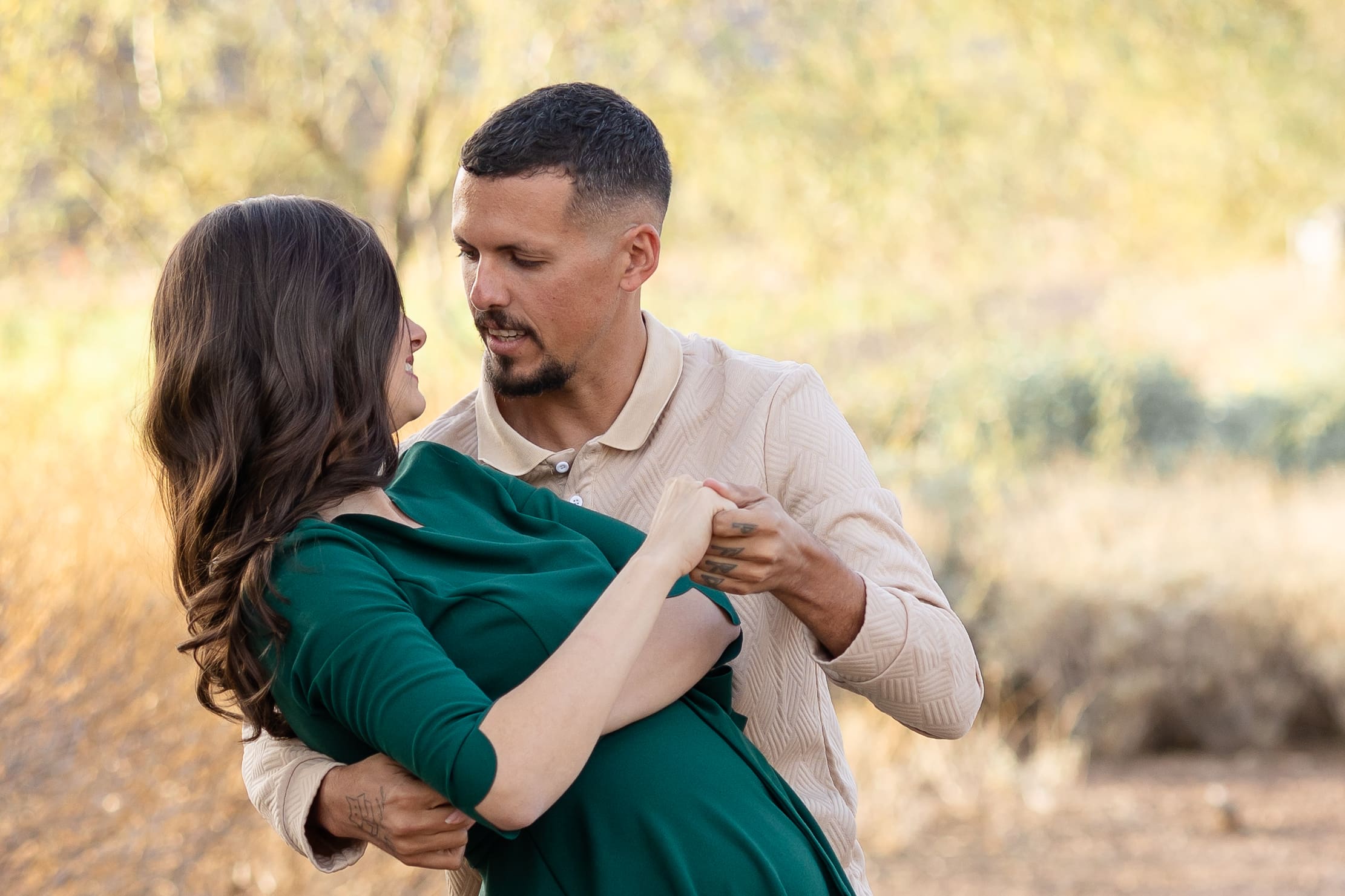 Man gently dips his partner while sharing a loving gaze during a golden hour family photo session outdoors.