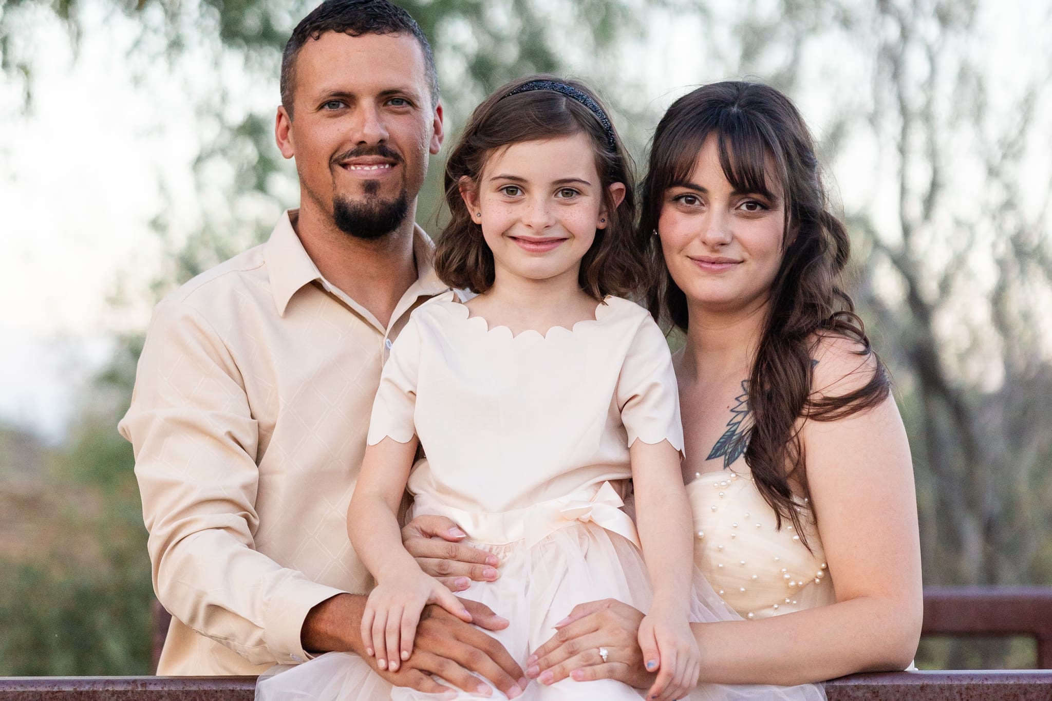 Christina Katelyn with her husband and daughter during a golden hour family photo session, wearing soft neutral tones. Warm, candid moment highlighting real motherhood and blended family life for a lifestyle and motherhood blog.